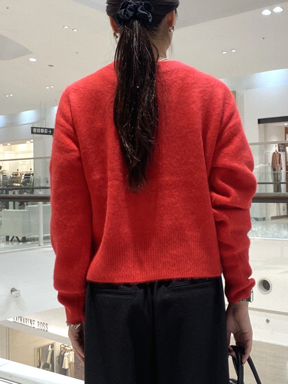 レッド系のカーディガン/ボレロ、ブラック系のスラックス、ブラック系のボストンバッグを着用したレディースの秋コーディネートの6枚目の写真