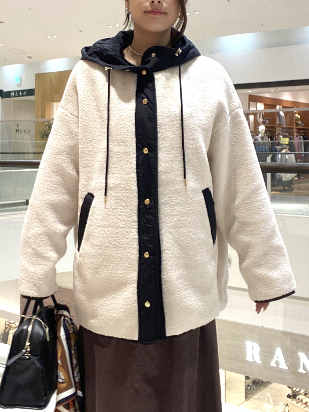 ホワイト系のその他アウター、ブラウン系のスカート、ブラック系のボストンバッグを着用したレディースの秋コーディネートの4枚目の写真