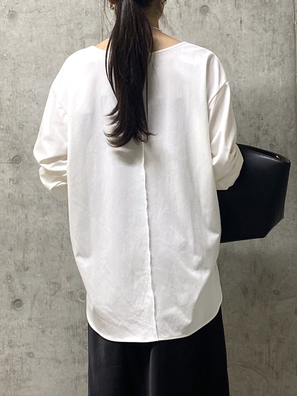 ブラック系のスカート、ホワイト系のTシャツ/カットソー、ブラック系のハンドバッグを着用したレディースの秋コーディネートの6枚目の写真