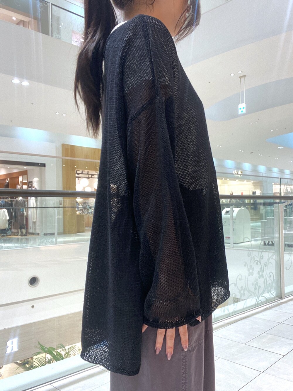 ブラック系のニット/セーター、ホワイト系のTシャツ/カットソー、ブラウン系のハンドバッグを着用したレディースの夏コーディネートの5枚目の写真