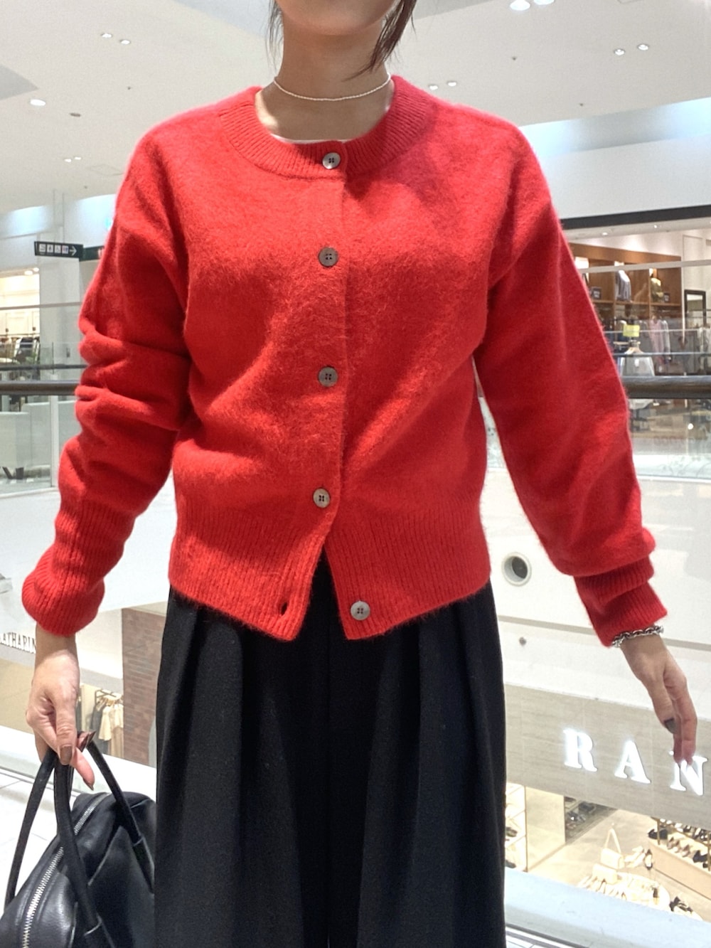 レッド系のカーディガン/ボレロ、ブラック系のスラックス、ブラック系のボストンバッグを着用したレディースの秋コーディネートの4枚目の写真