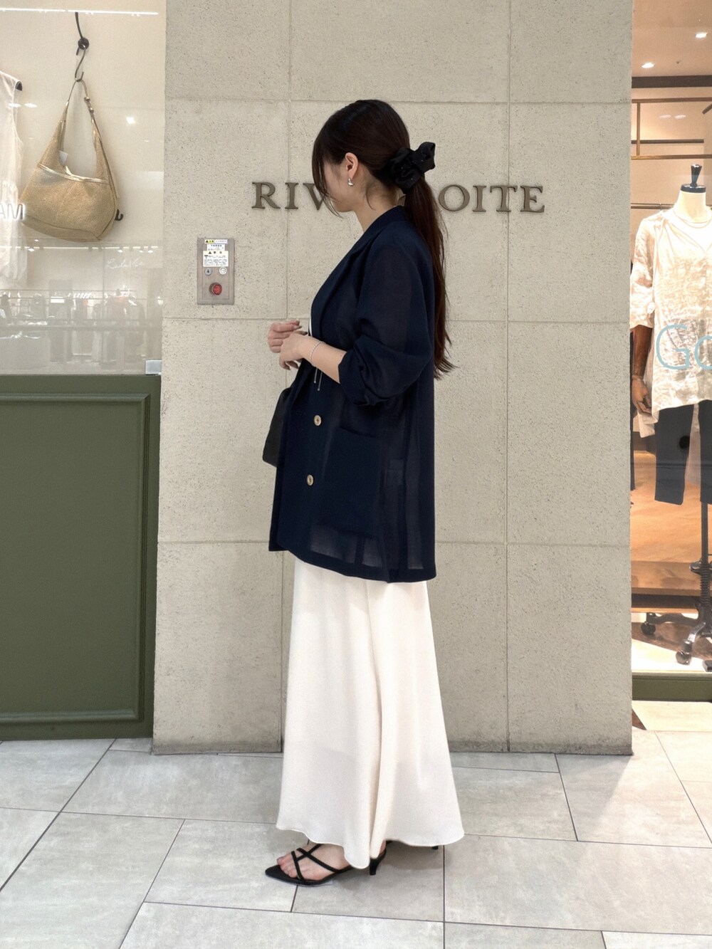 ブラック系のボストンバッグ、ホワイト系のスカート、ブラック系のサンダルを着用したレディースの夏コーディネートの2枚目の写真