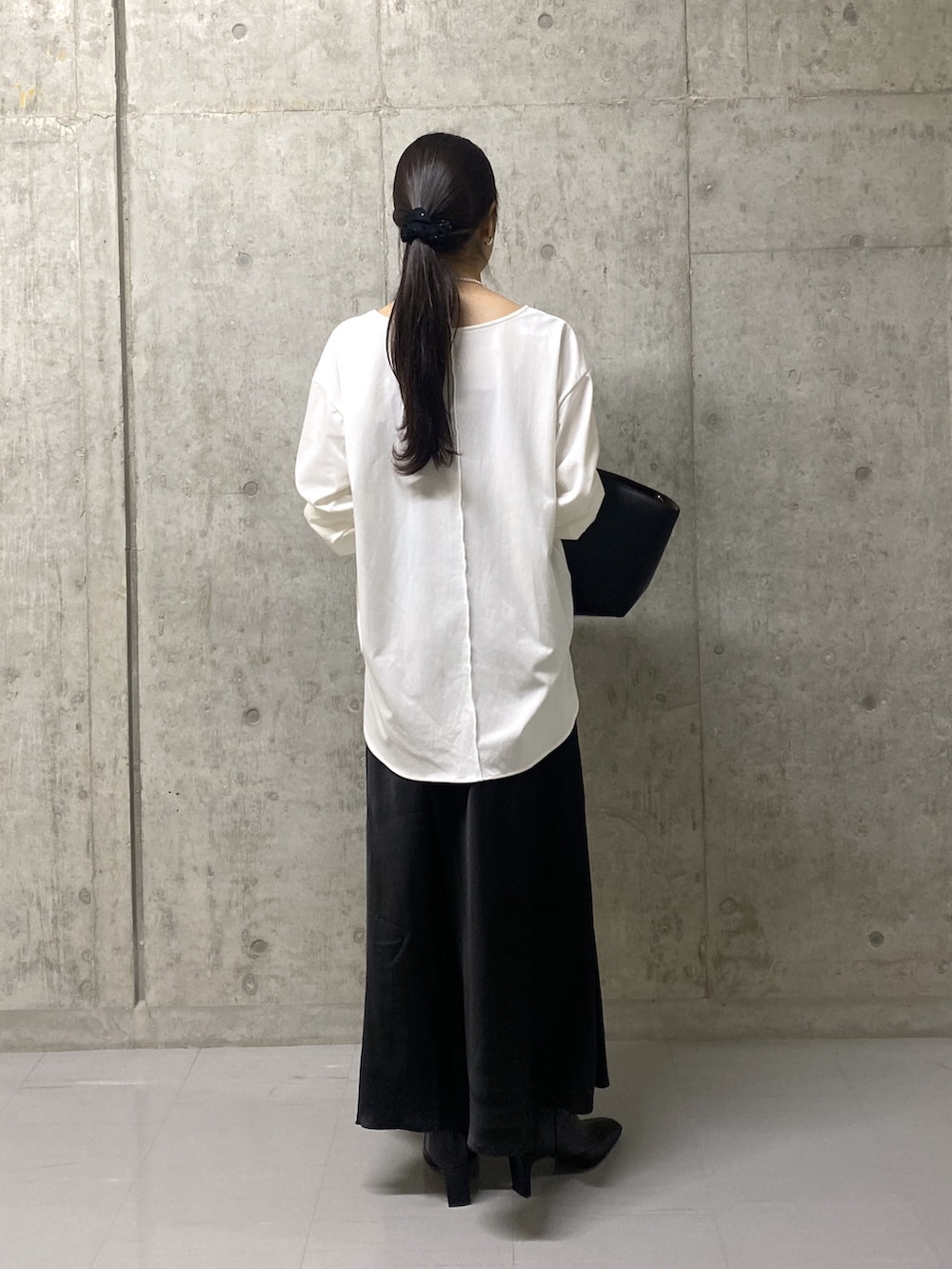 ブラック系のスカート、ホワイト系のTシャツ/カットソー、ブラック系のハンドバッグを着用したレディースの秋コーディネートの3枚目の写真
