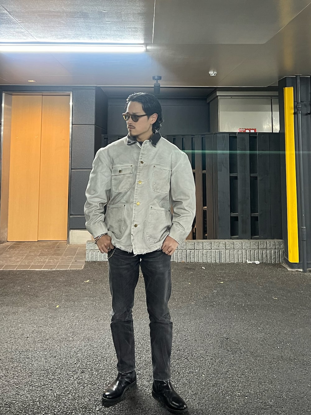 ブラック系のデニムパンツ、ホワイト系のカバーオール、ブラック系のブーツを着用したメンズの冬コーディネートの2枚目の写真