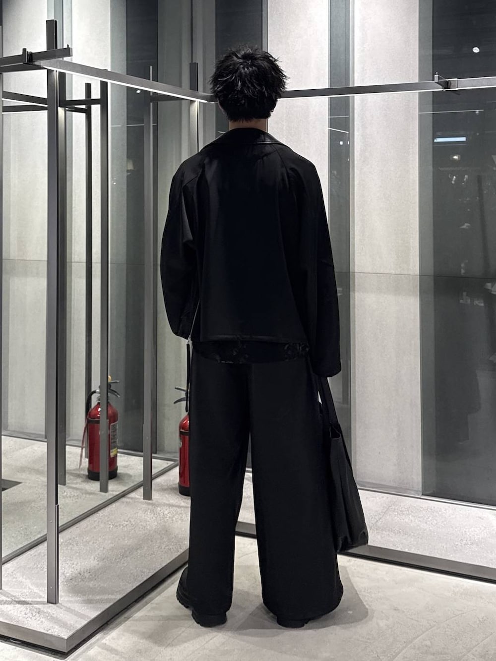 ブラック系のドレスシューズ、ブラック系のブルゾン、ブラック系のトートバッグを着用したメンズの春コーディネートの2枚目の写真