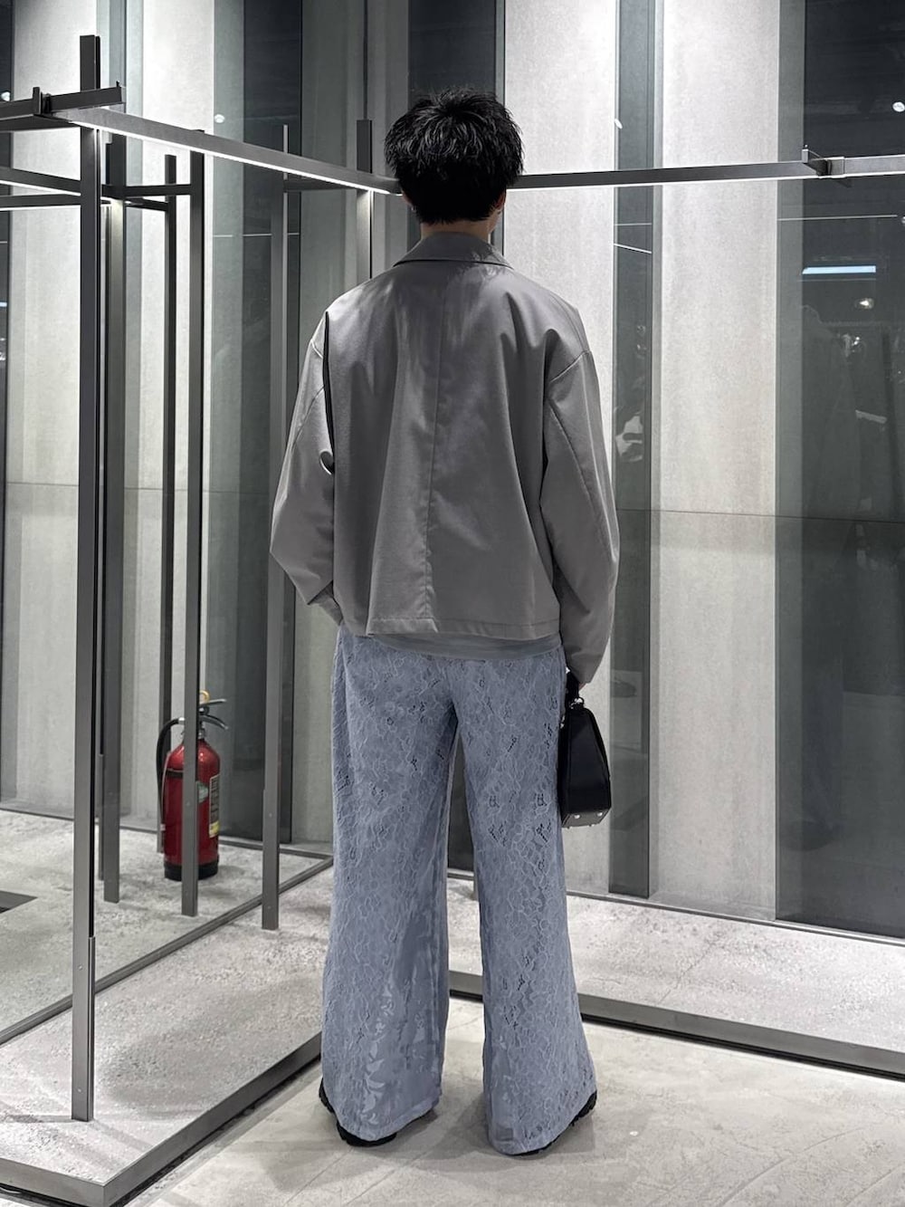 グレー系のブルゾン、ブラック系のドレスシューズ、ブラック系のショルダーバッグを着用したメンズの春コーディネートの2枚目の写真