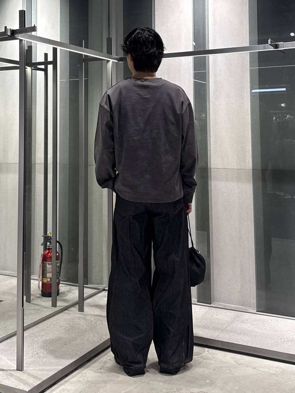 ブラック系のショルダーバッグ、グレー系のTシャツ/カットソー、ブラック系のスニーカーを着用したメンズの秋コーディネートの2枚目の写真