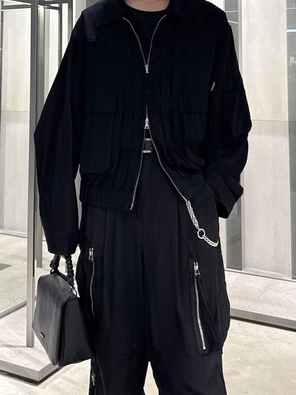ブラック系のショルダーバッグ、ブラック系のブルゾン、ブラック系のTシャツ/カットソーを着用したメンズの夏コーディネートの2枚目の写真