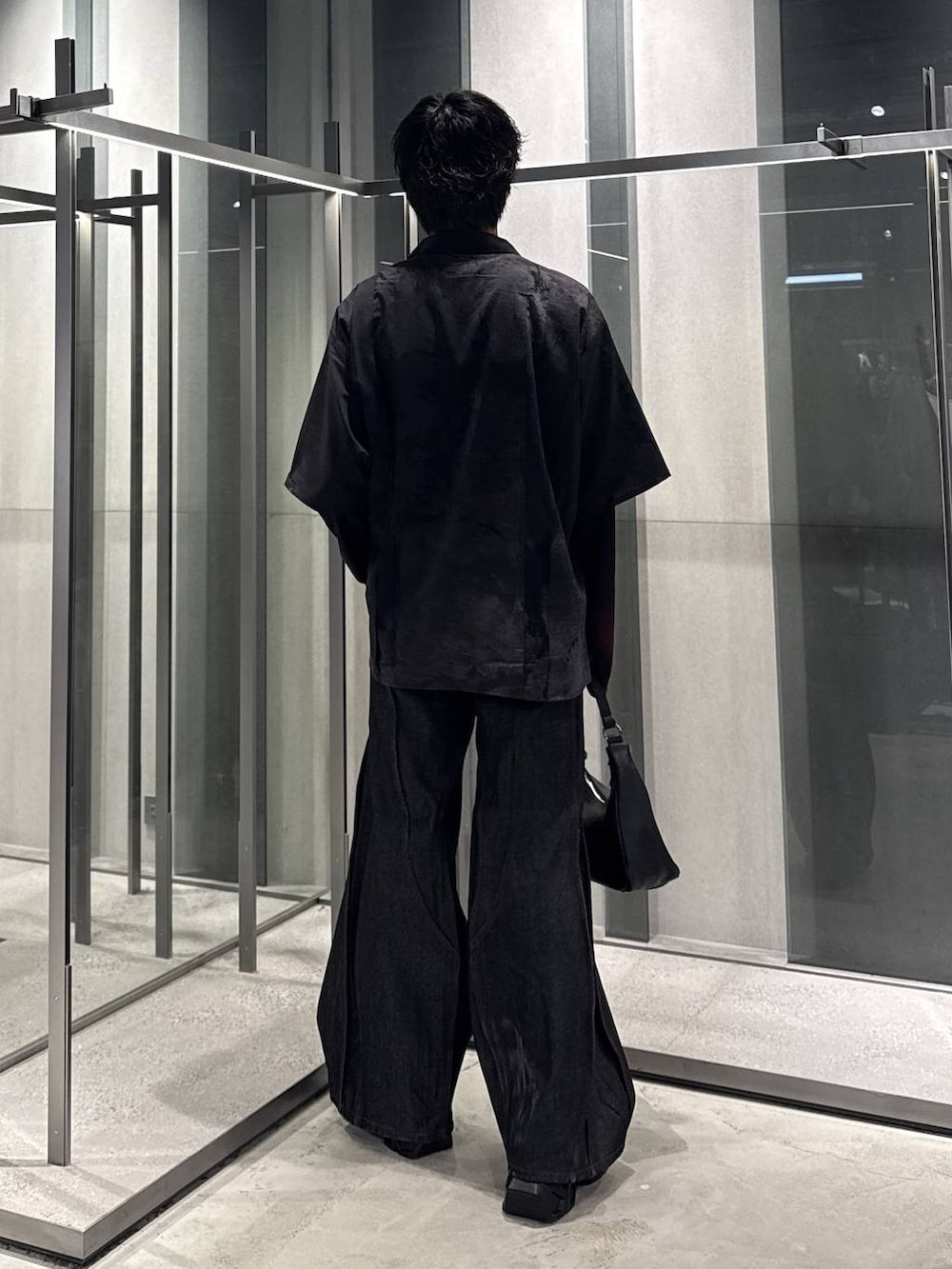 オレンジ系のTシャツ/カットソー、ブラック系のスニーカー、ブラック系のデニムパンツを着用したメンズの秋コーディネートの2枚目の写真