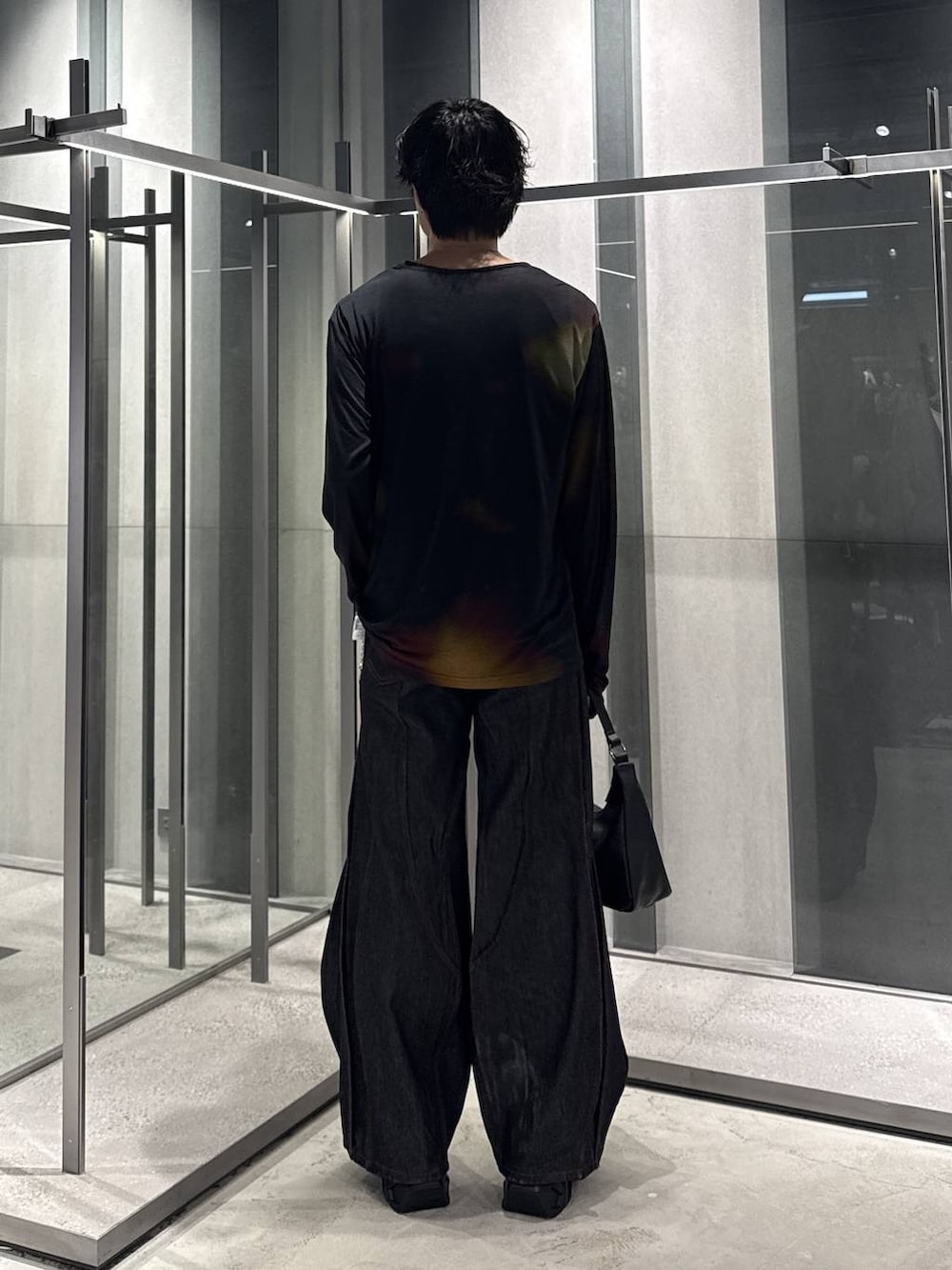 オレンジ系のTシャツ/カットソー、ブラック系のスニーカー、ブラック系のデニムパンツを着用したメンズの秋コーディネートの2枚目の写真