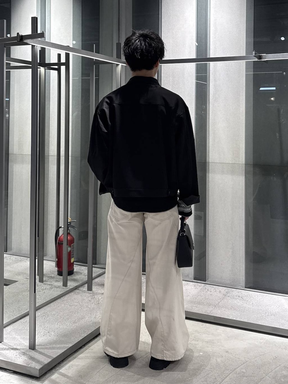 ホワイト系のデニムパンツ、ブラック系のドレスシューズ、ブラック系のブルゾンを着用したメンズの春コーディネートの2枚目の写真