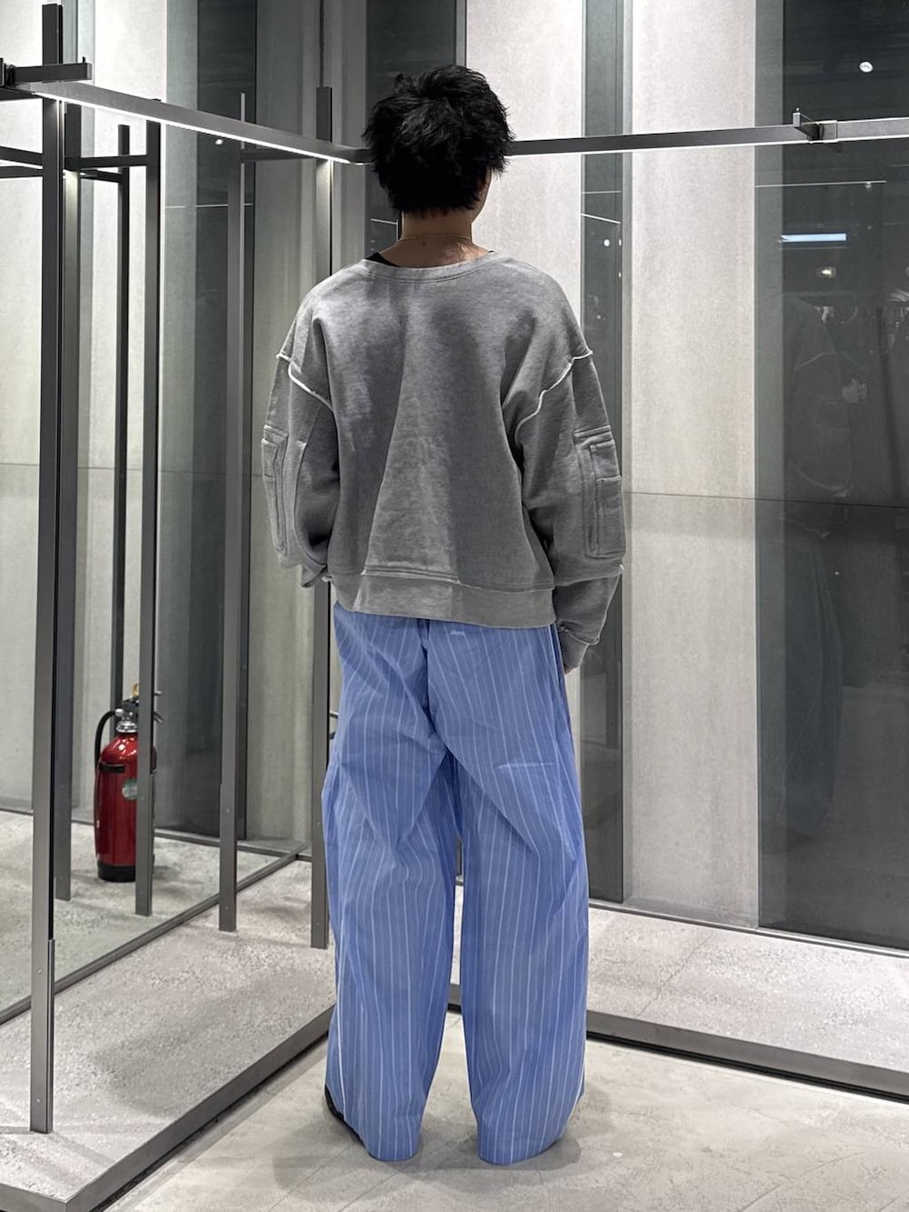 ブラック系のTシャツ/カットソー、ブルー系のスラックス、グレー系のスウェットを着用したメンズの春コーディネートの2枚目の写真