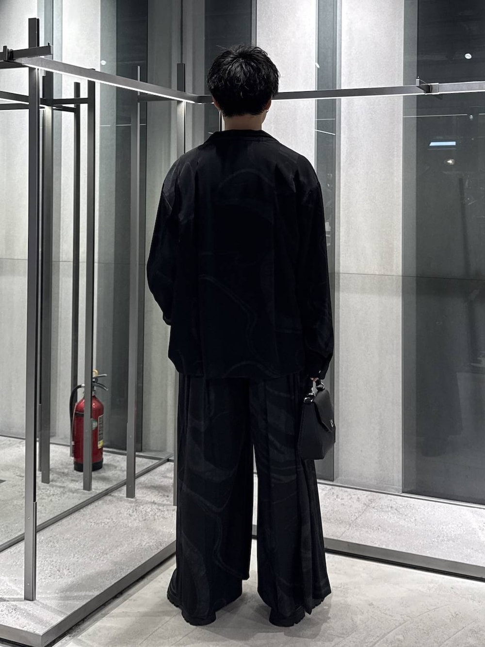 グレー系のその他パンツ、ブラック系のドレスシューズ、ブラック系のショルダーバッグを着用したメンズの春コーディネートの2枚目の写真