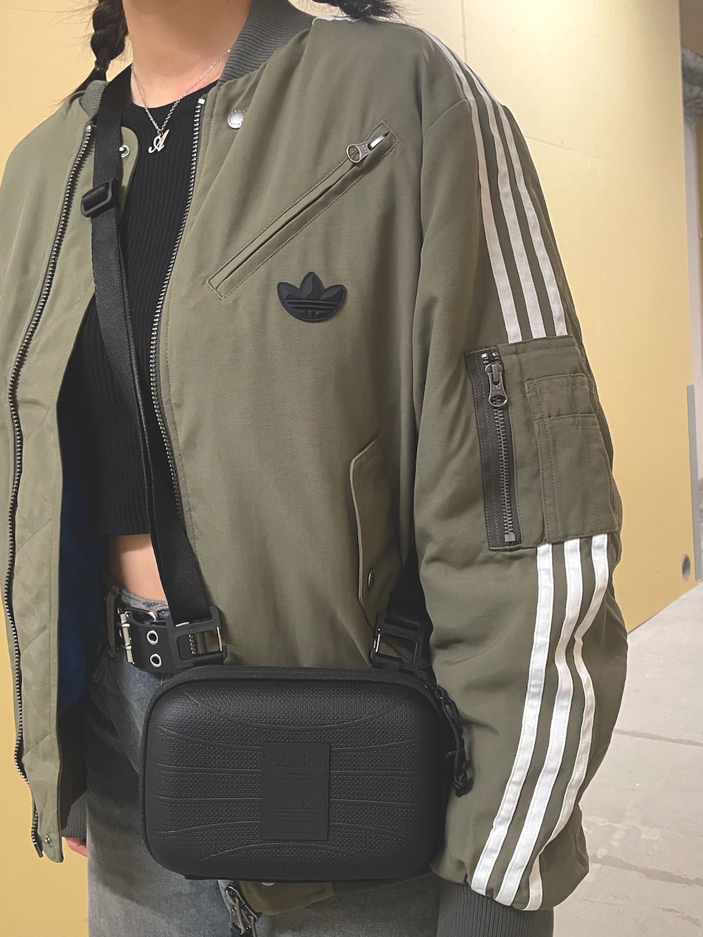 グリーン系のダウンジャケット/コート、ベージュ系のスニーカー、ブラック系のショルダーバッグを着用したレディースの秋コーディネートの3枚目の写真