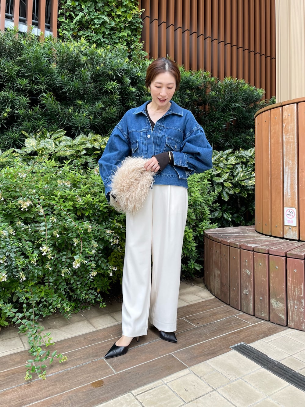 ブルー系のデニムジャケット、ベージュ系のショルダーバッグ、ホワイト系のその他パンツを着用したレディースの秋コーディネートの2枚目の写真