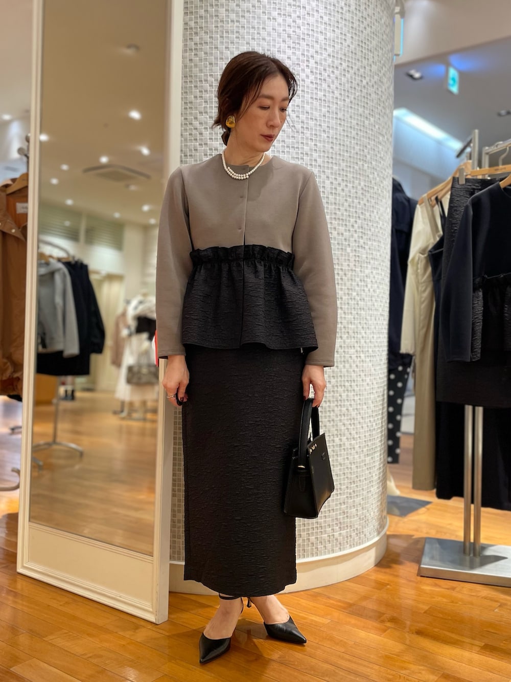 グリーン系のブルゾン、ブラック系のスカート、ブラック系のショルダーバッグを着用したレディースの秋コーディネートの4枚目の写真