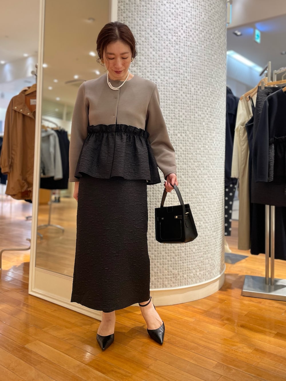 グリーン系のブルゾン、ブラック系のスカート、ブラック系のショルダーバッグを着用したレディースの秋コーディネートの6枚目の写真