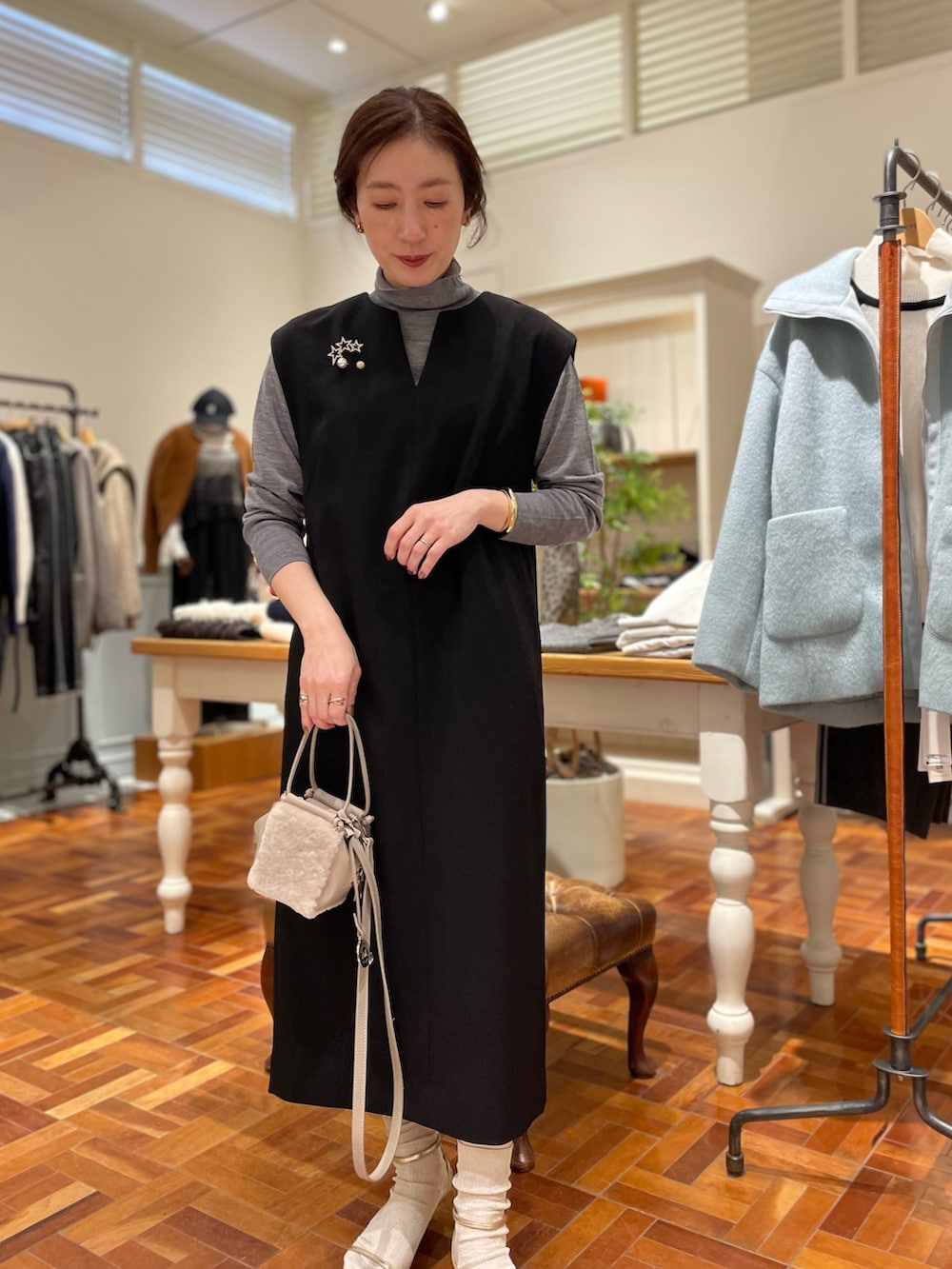 ブラック系のワンピース、グレー系のニット/セーター、ベージュ系のショルダーバッグを着用したレディースの冬コーディネートの2枚目の写真