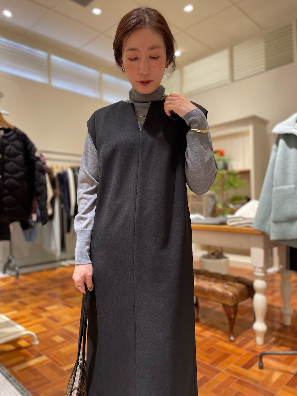 ブラック系のワンピース、グレー系のニット/セーター、ベージュ系のショルダーバッグを着用したレディースの冬コーディネートの6枚目の写真