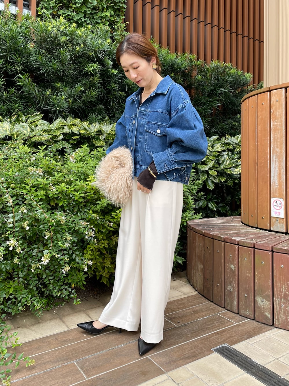 ブルー系のデニムジャケット、ベージュ系のショルダーバッグ、ホワイト系のその他パンツを着用したレディースの秋コーディネートの3枚目の写真