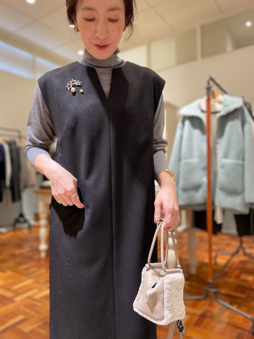 ブラック系のワンピース、グレー系のニット/セーター、ベージュ系のショルダーバッグを着用したレディースの冬コーディネートの4枚目の写真