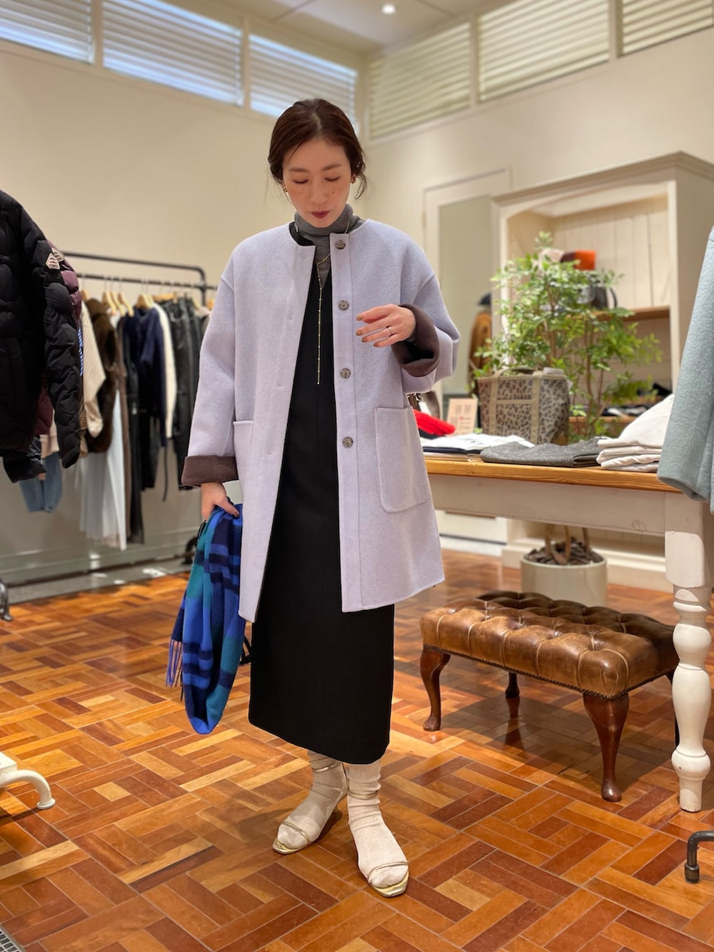 ブラウン系のノーカラーコート、ブラック系のワンピース、グレー系のニット/セーターを着用したレディースの冬コーディネートの2枚目の写真