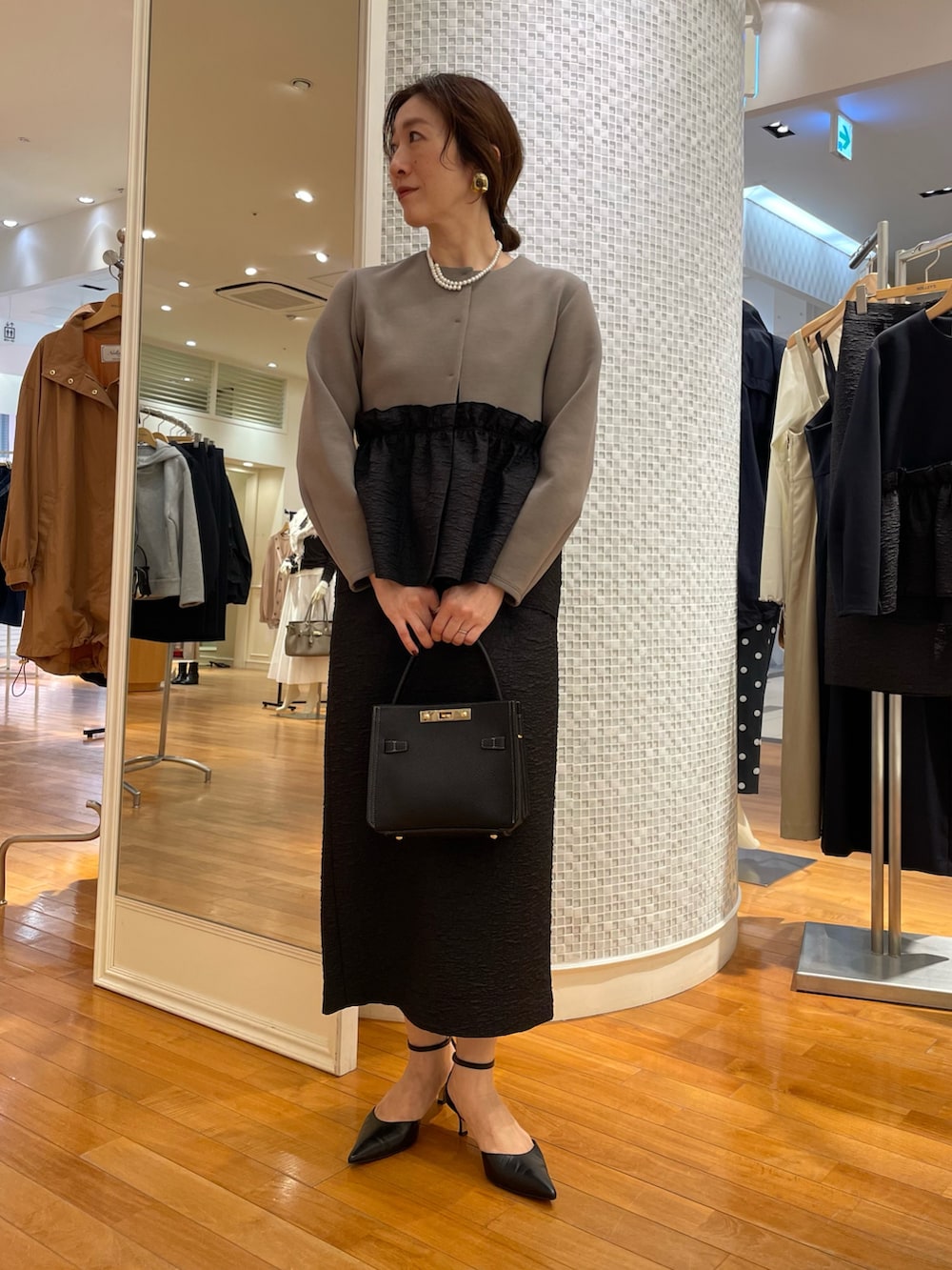 グリーン系のブルゾン、ブラック系のスカート、ブラック系のショルダーバッグを着用したレディースの秋コーディネートの2枚目の写真