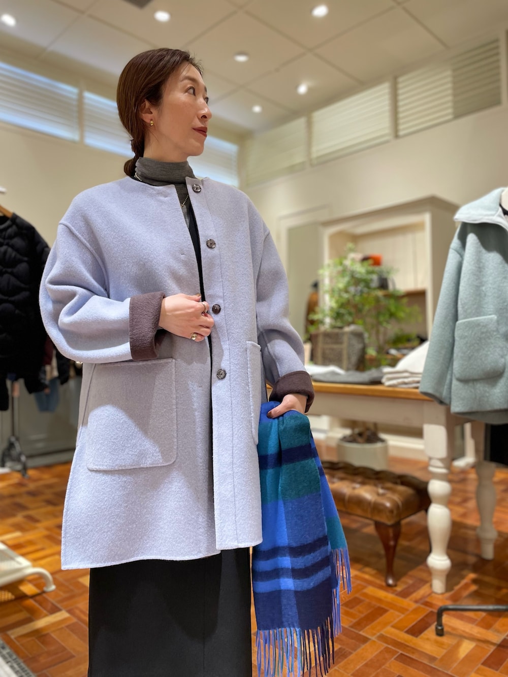 ブラウン系のノーカラーコート、ブラック系のワンピース、グレー系のニット/セーターを着用したレディースの冬コーディネートの5枚目の写真