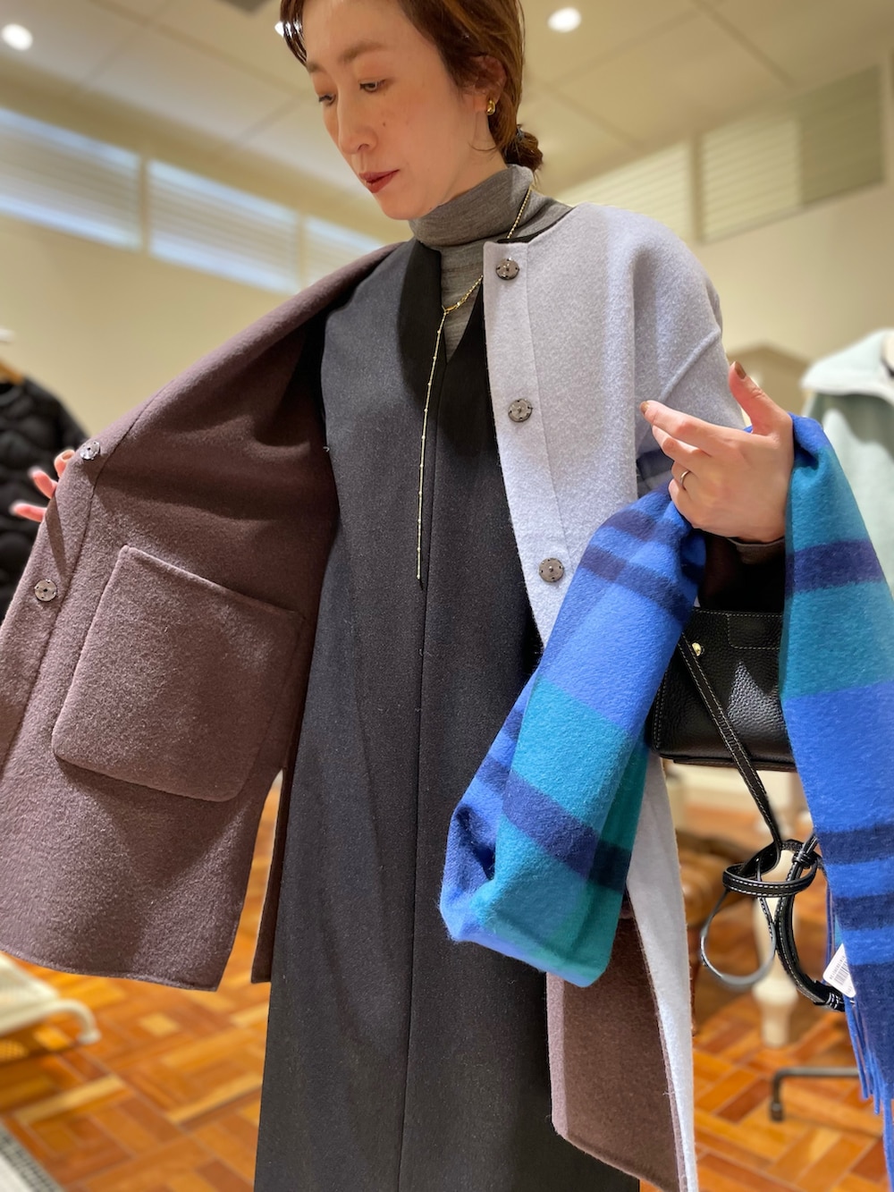 ブラウン系のノーカラーコート、ブラック系のワンピース、グレー系のニット/セーターを着用したレディースの冬コーディネートの6枚目の写真