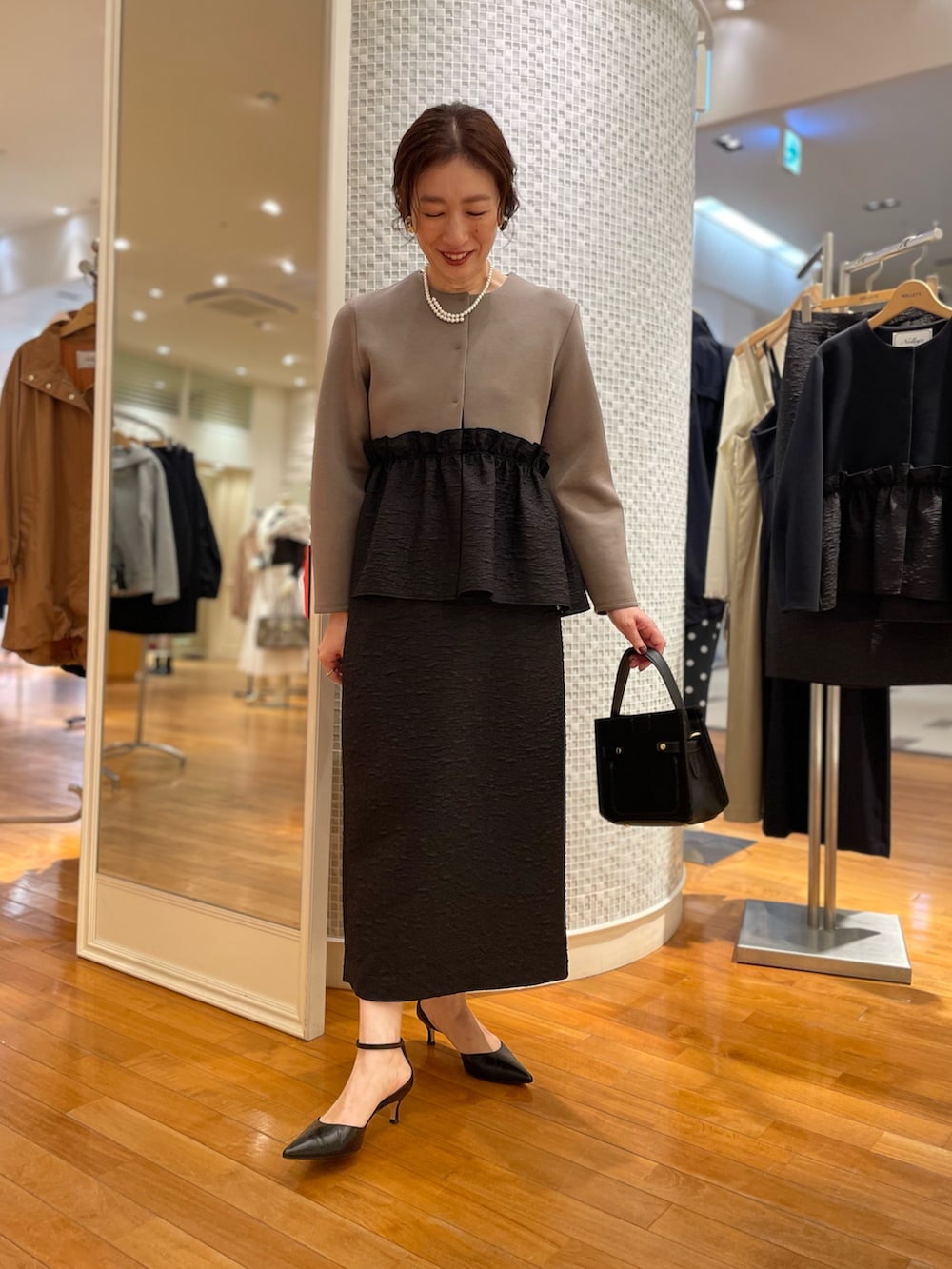 グリーン系のブルゾン、ブラック系のスカート、ブラック系のショルダーバッグを着用したレディースの秋コーディネートの9枚目の写真