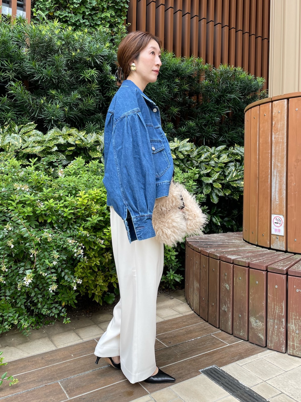 ブルー系のデニムジャケット、ベージュ系のショルダーバッグ、ホワイト系のその他パンツを着用したレディースの秋コーディネートの5枚目の写真