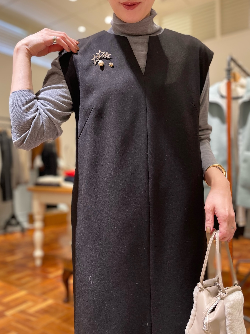 ブラック系のワンピース、グレー系のニット/セーター、ベージュ系のショルダーバッグを着用したレディースの冬コーディネートの3枚目の写真