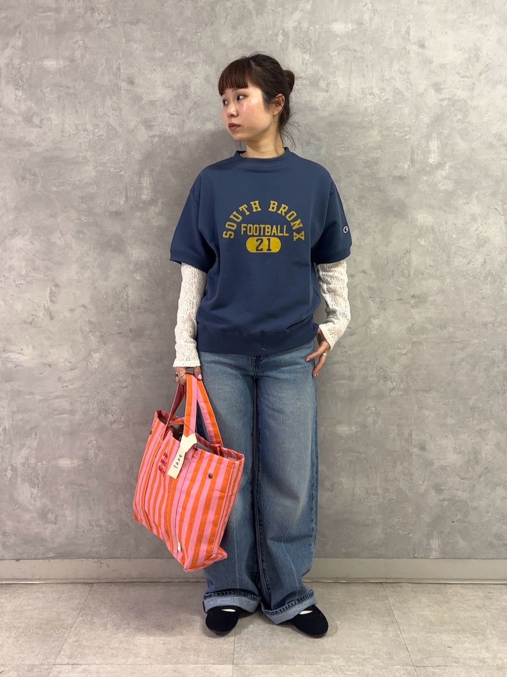 ピンク系のトートバッグ、ブルー系のデニムパンツ、ホワイト系のTシャツ/カットソーを着用したレディースの春コーディネートの2枚目の写真