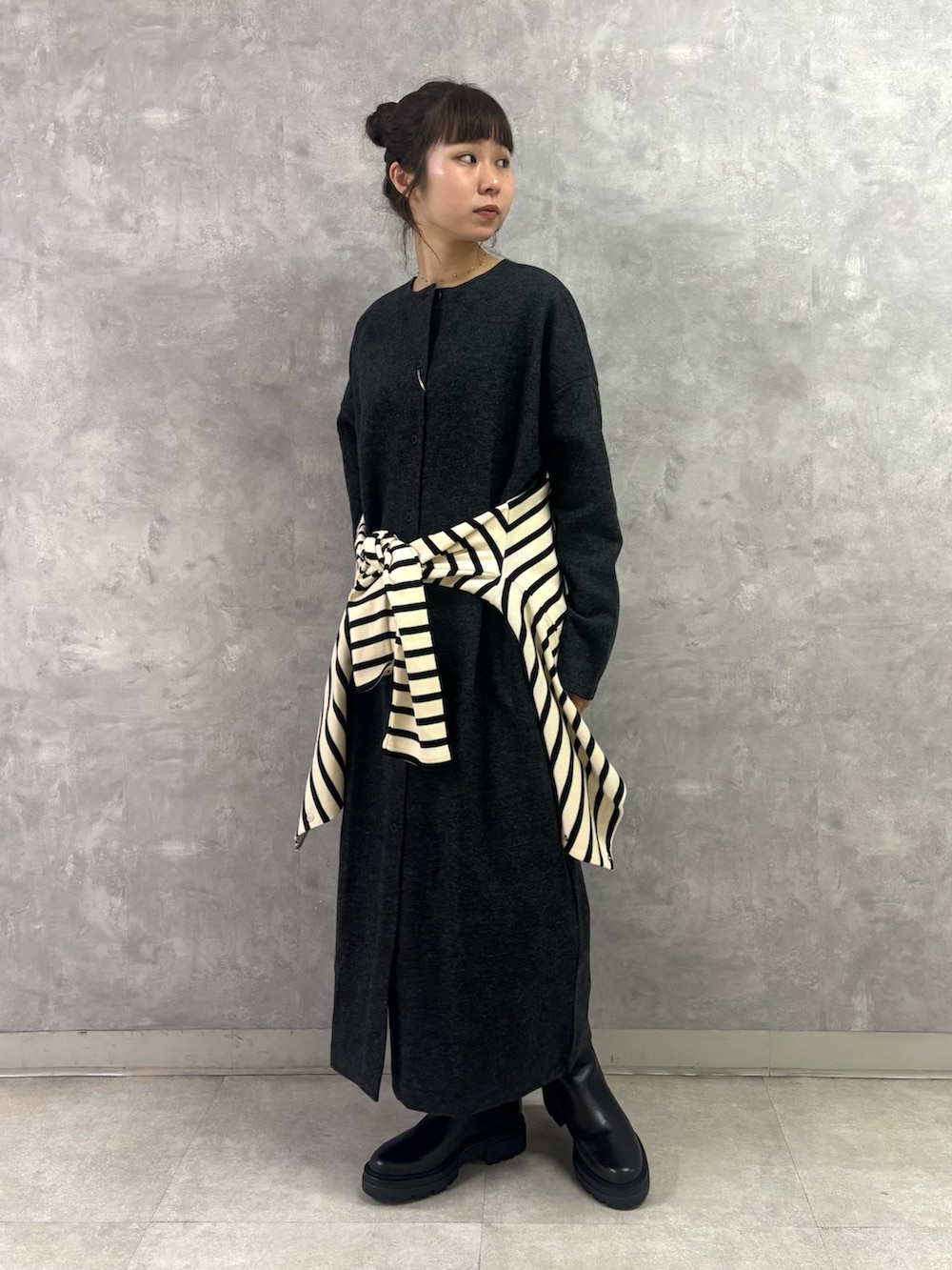 ブラック系のブーツ、ホワイト系のトートバッグ、グレー系のワンピースを着用したレディースの秋コーディネートの4枚目の写真