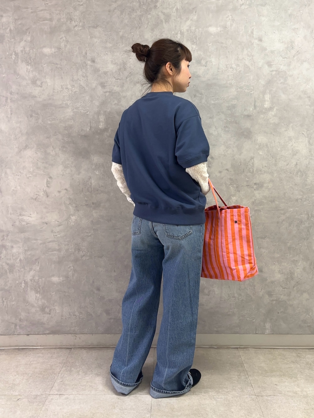 ピンク系のトートバッグ、ブルー系のデニムパンツ、ホワイト系のTシャツ/カットソーを着用したレディースの春コーディネートの3枚目の写真