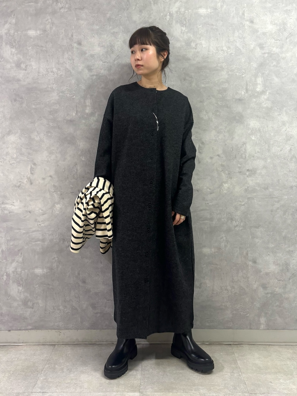 ブラック系のブーツ、ホワイト系のトートバッグ、グレー系のワンピースを着用したレディースの秋コーディネートの5枚目の写真