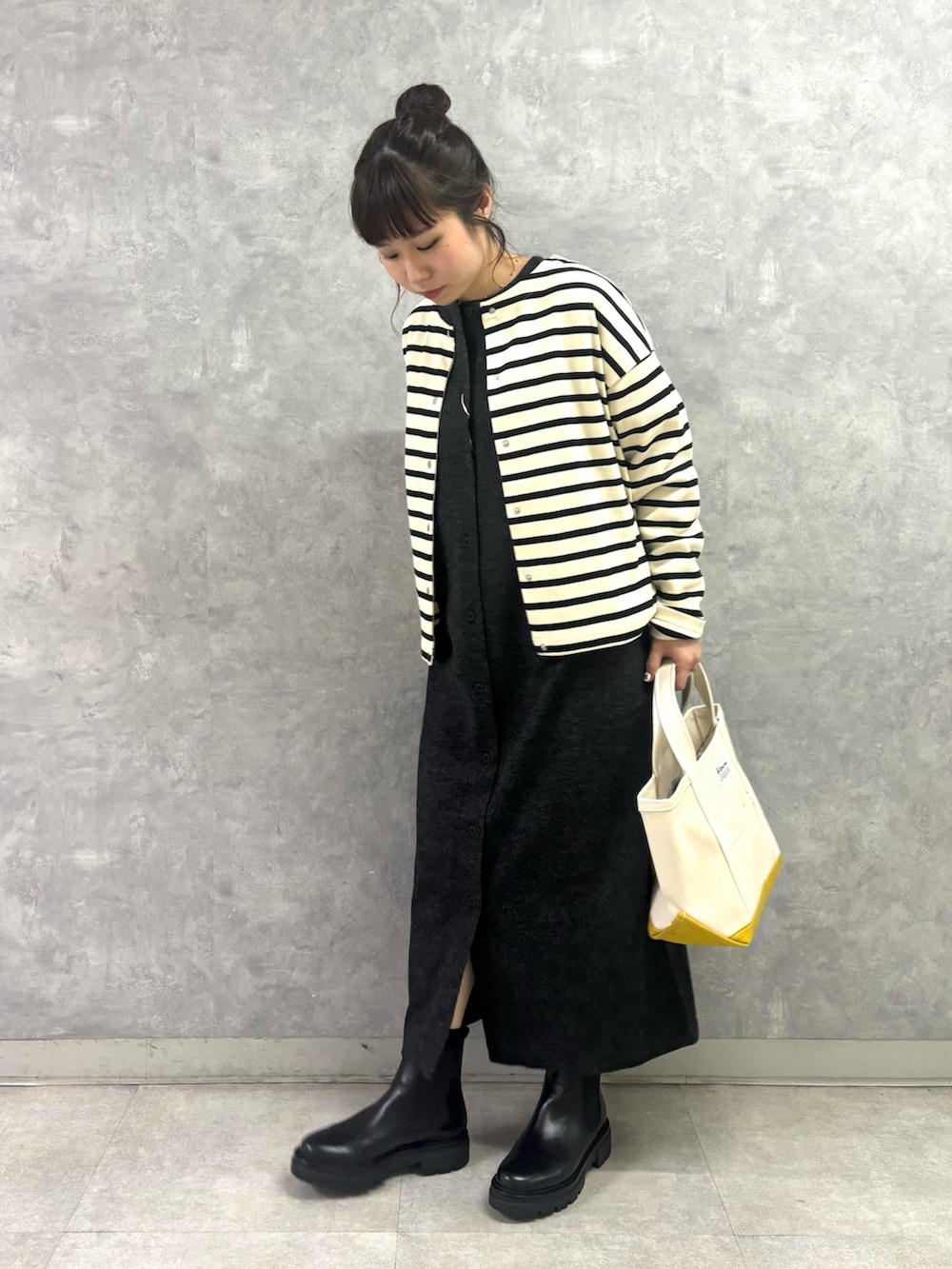 ブラック系のブーツ、ホワイト系のトートバッグ、グレー系のワンピースを着用したレディースの秋コーディネートの2枚目の写真