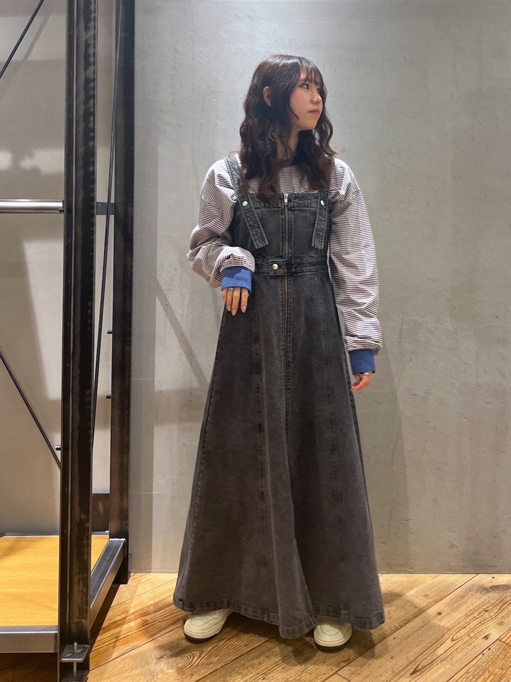 ブラック系のジャンパースカート、ブルー系のトップスを着用したレディースの春コーディネートの2枚目の写真