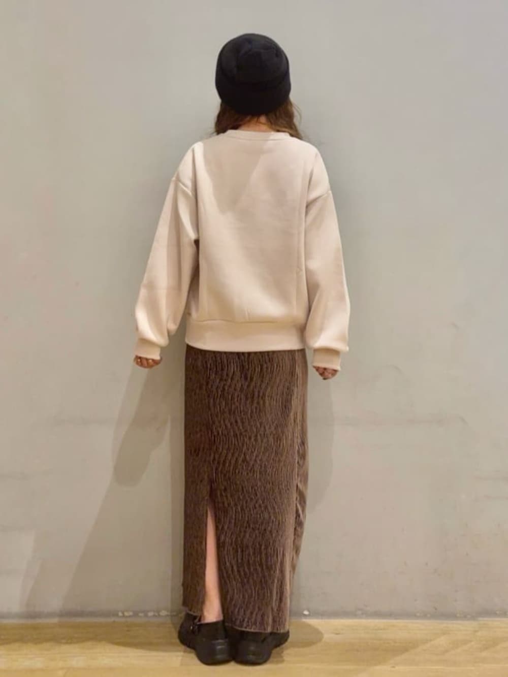 ホワイト系のスウェット、ブラウン系のスカート、ブラック系のスニーカーを着用したレディースの秋コーディネートの2枚目の写真