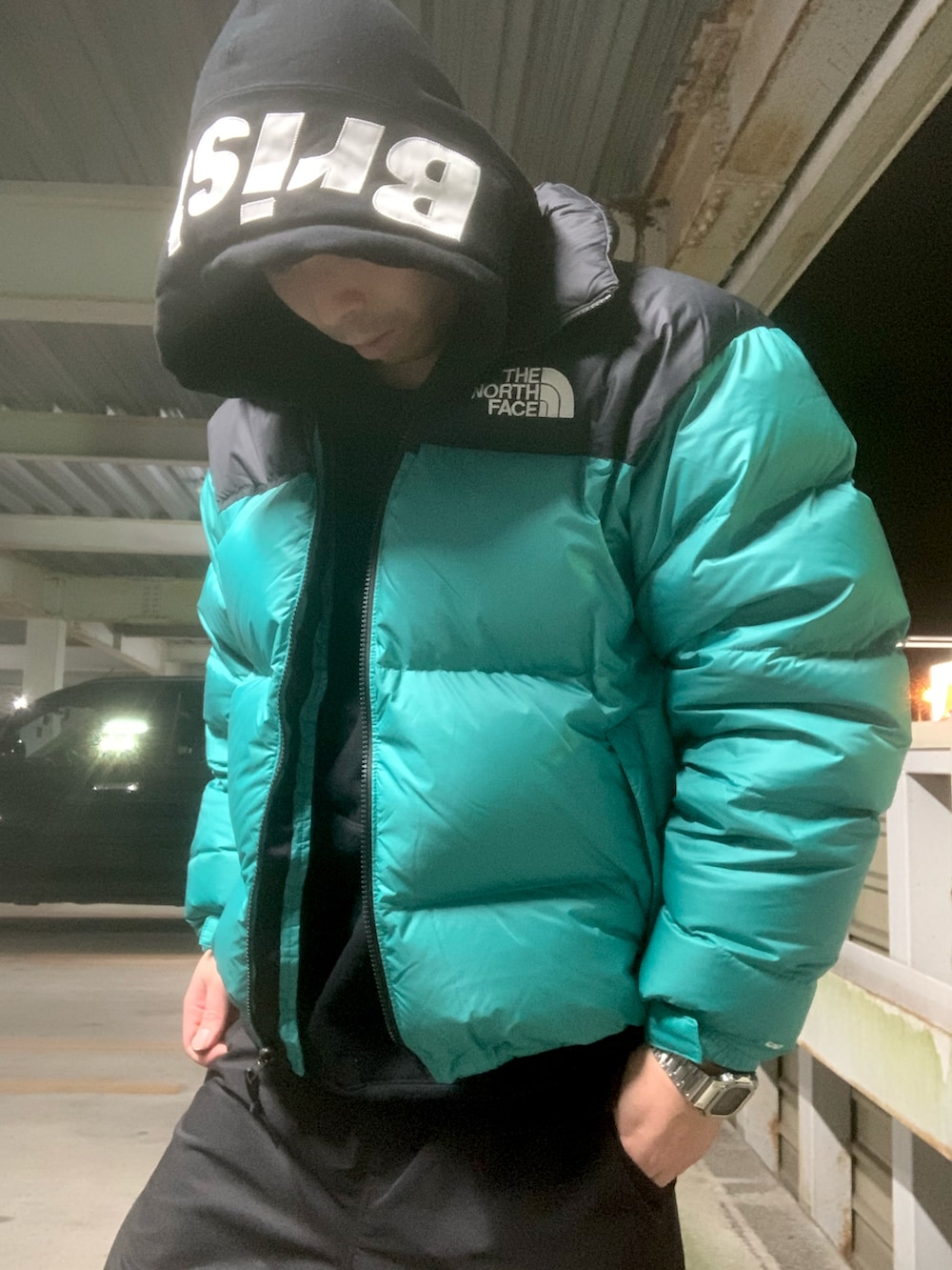 グリーン系のダウンジャケット/コート、ブラック系のパーカー、ブラック系のカーゴパンツを着用したメンズの冬コーディネートの3枚目の写真