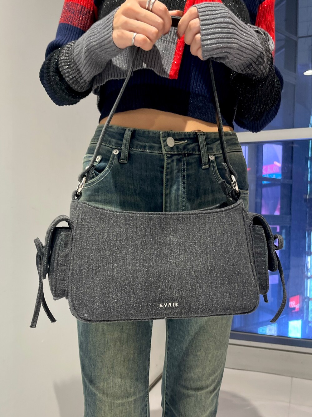 レッド系のニット/セーター、ブルー系のデニムパンツ、ブラック系のハンドバッグを着用したレディースの秋コーディネートの6枚目の写真