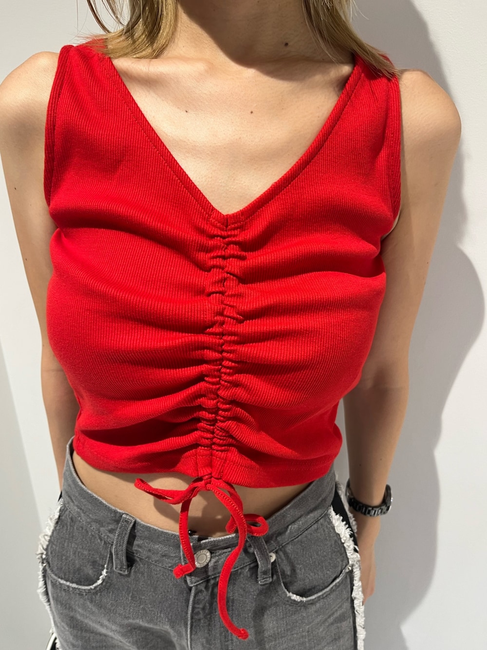 レッド系のタンクトップ、ブラック系のデニムパンツ、ブラック系のサンダルを着用したレディースの夏コーディネートの2枚目の写真