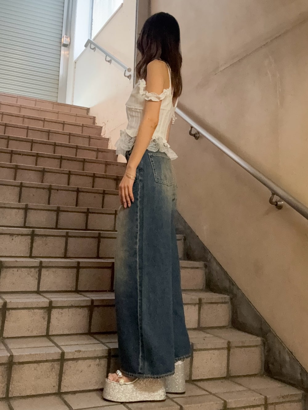 ホワイト系のキャミソール、ブルー系のデニムパンツ、シルバー系のサンダルを着用したレディースの春コーディネートの2枚目の写真