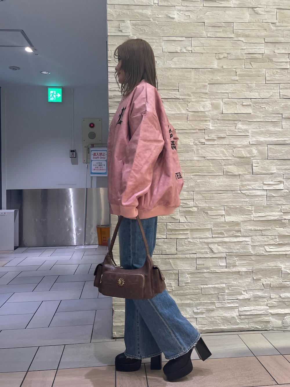 ピンク系のスタジャン、グレー系のTシャツ/カットソー、ブルー系のデニムパンツを着用したレディースの冬コーディネートの2枚目の写真