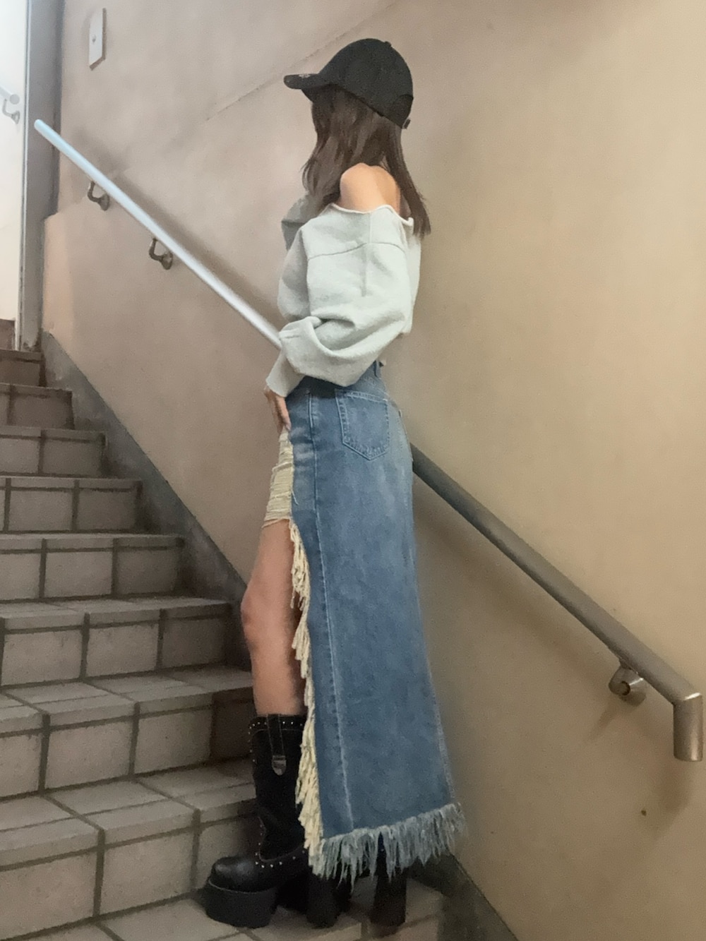 グレー系のスウェット、ブルー系のデニムスカート、ブラック系のキャップを着用したレディースの春コーディネートの2枚目の写真