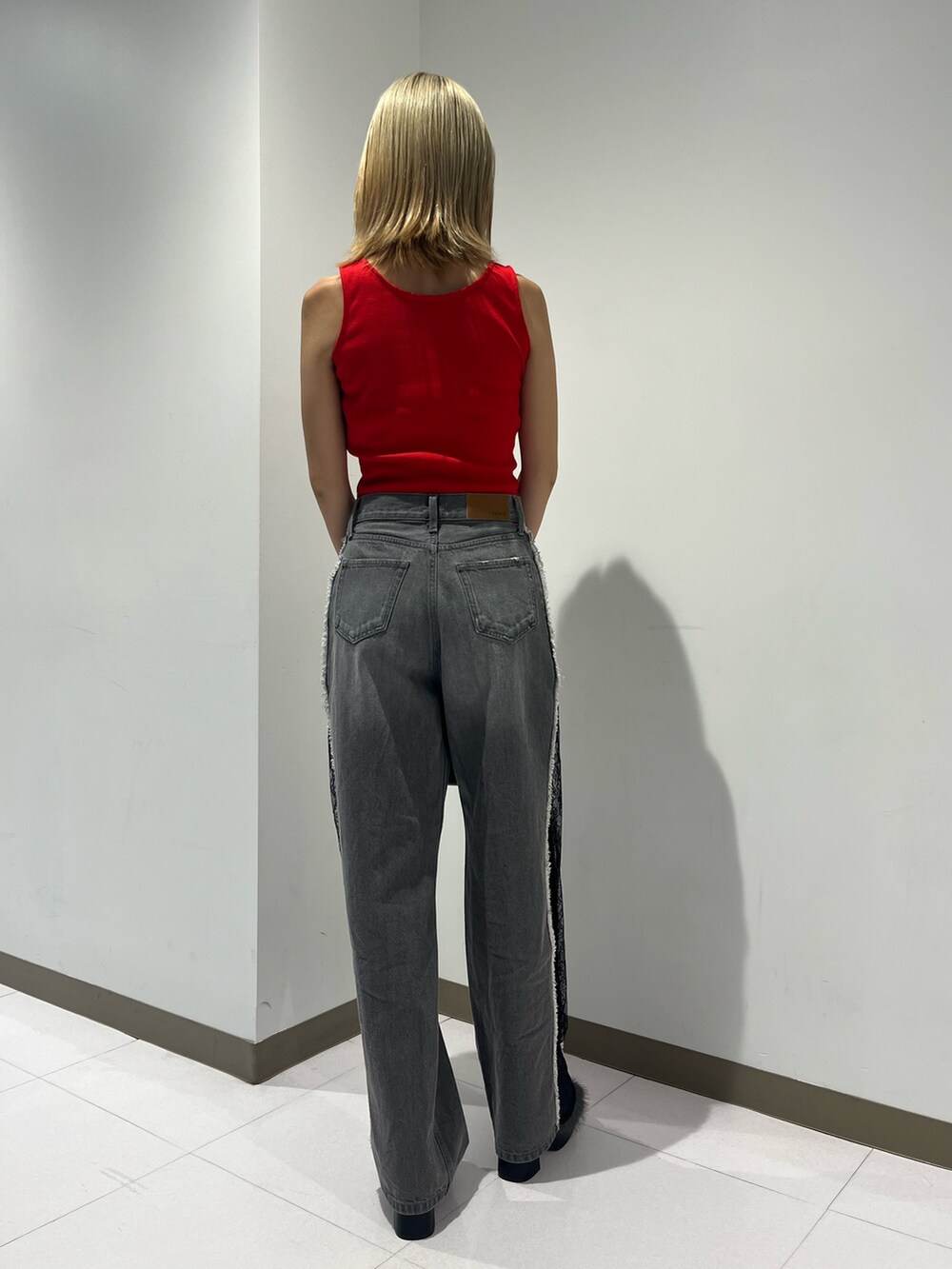 レッド系のタンクトップ、ブラック系のデニムパンツ、ブラック系のサンダルを着用したレディースの夏コーディネートの5枚目の写真