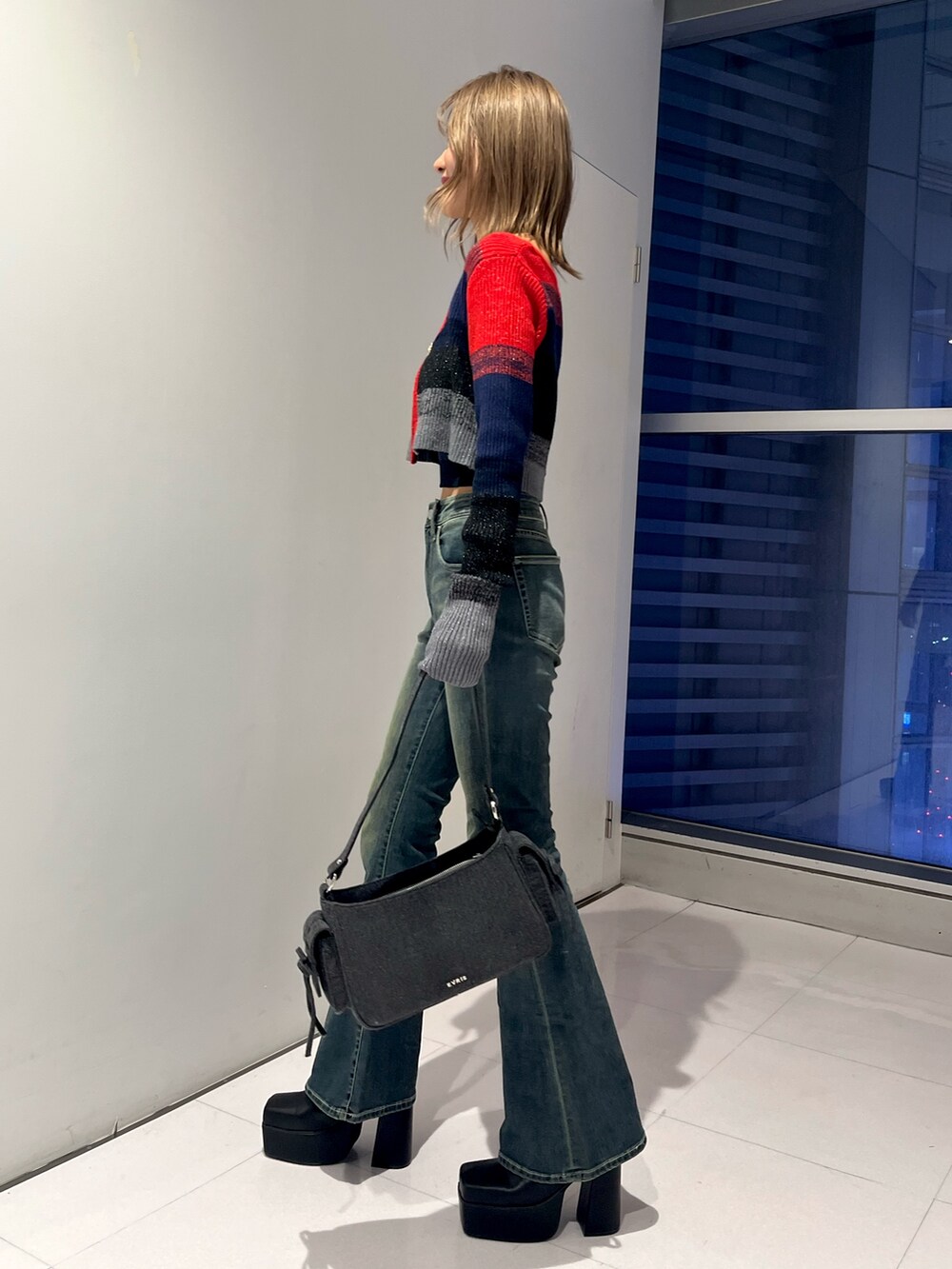 レッド系のニット/セーター、ブルー系のデニムパンツ、ブラック系のハンドバッグを着用したレディースの秋コーディネートの2枚目の写真