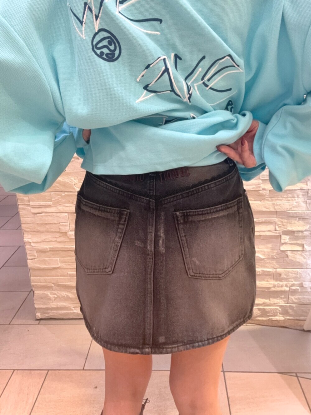 ブルー系のTシャツ/カットソー、ブラック系のデニムスカート、ブラウン系のブーツを着用したレディースの秋コーディネートの7枚目の写真