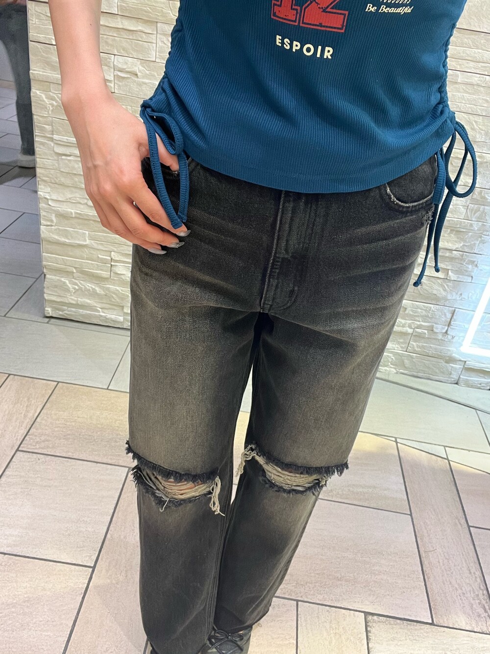 ブルー系のタンクトップ、ブラック系のデニムパンツ、グリーン系のサンダルを着用したレディースの春コーディネートの5枚目の写真