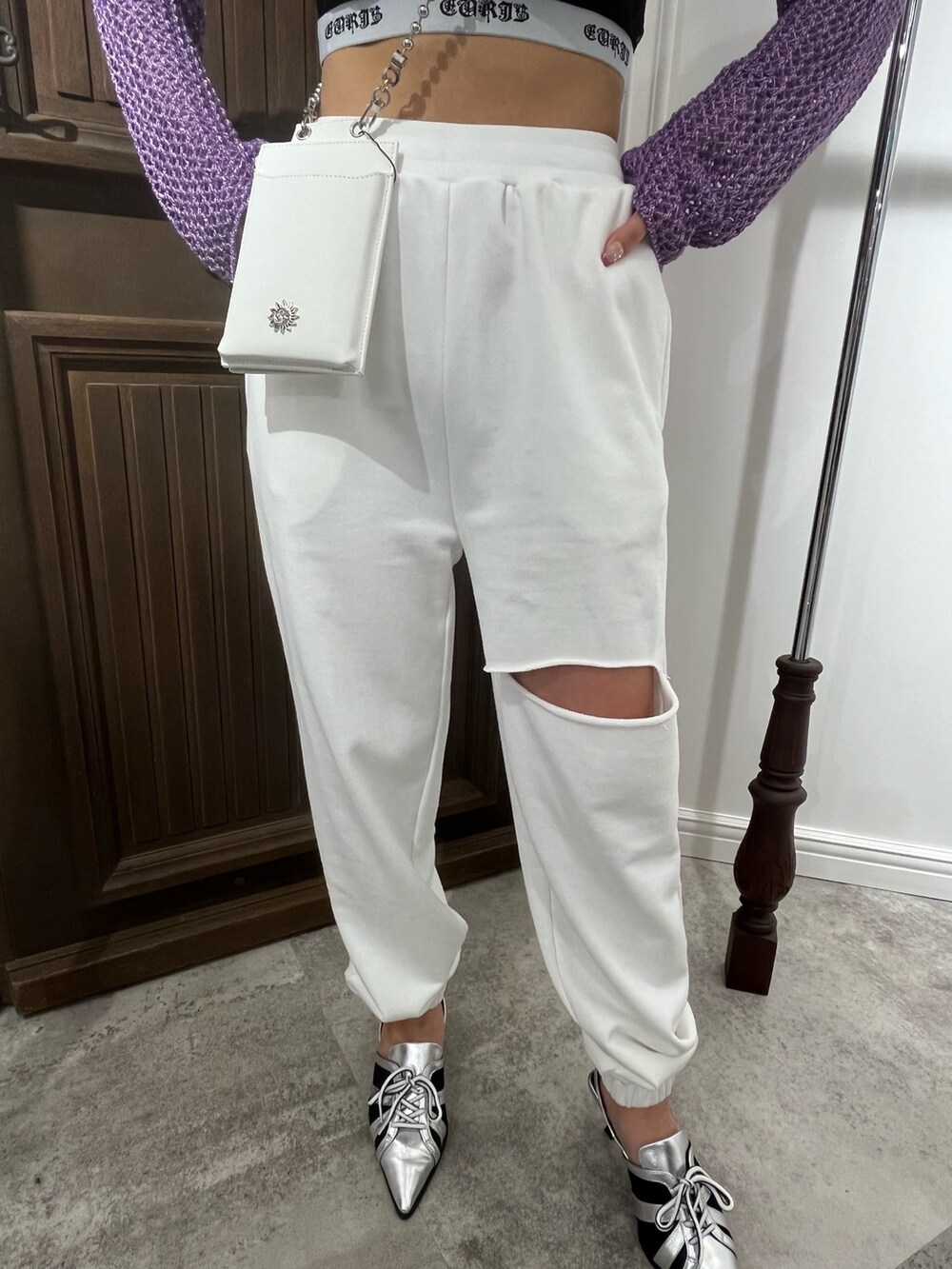 パープル系のニット/セーター、ブラック系のキャミソール、ホワイト系のショルダーバッグを着用したレディースの春コーディネートの4枚目の写真